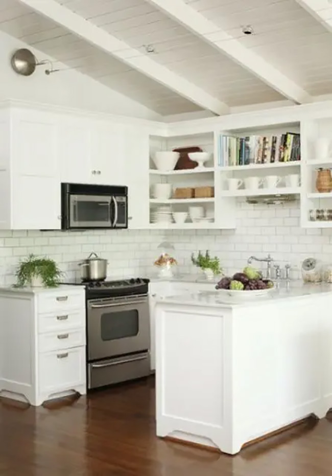 These simple white shelves fit neatly into the corner near the stove. They hold everyday plates and bowls within easy reach. The open no door kitchen cabinet design helps the small kitchen feel much bigger under the tall ceiling.