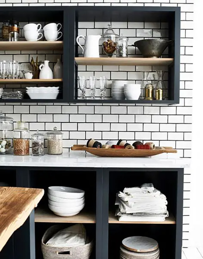 Black open shelves stand out boldly against the classic white subway tile backsplash. They provide easy access to everyday glasses and bowls while adding a modern industrial vibe. The dark color frames the white dishes beautifully.