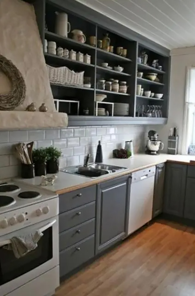 Slate blue cabinets bring a calm and cool feeling to this country-style kitchen. The upper cabinets have no doors, turning them into open racks for plates and jars. It’s a practical way to keep everything visible and organized.