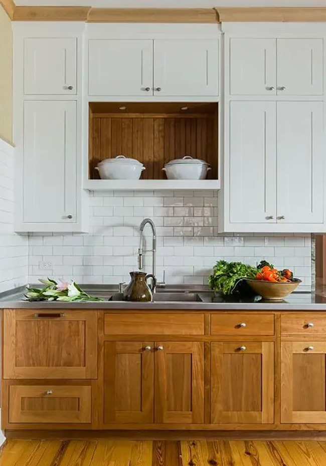 A warm wood niche is built into the center of the white upper cabinets. It creates a beautiful focal point for displaying large white serving bowls. The wood tone matches the lower cabinets, tying the whole design together.