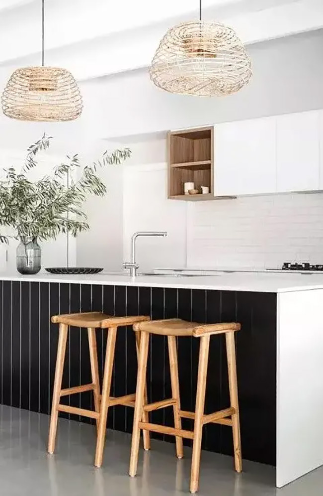 A small wooden box shelf sits perfectly in the center of the cabinets. It adds a warm touch to the modern black and white kitchen island. The open shelf is just the right size for a few glasses or small bowls.