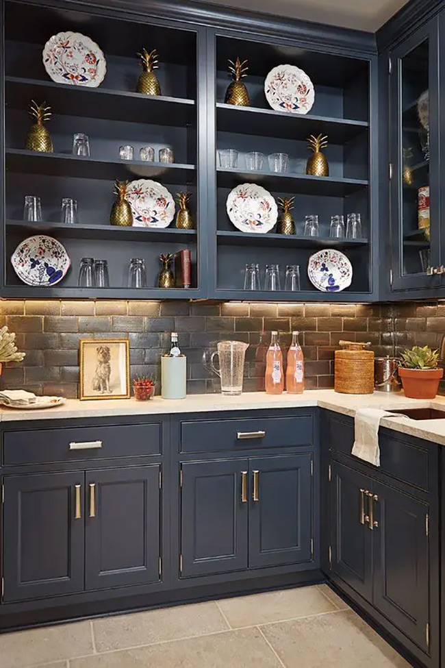 Deep teal cabinets give this kitchen an elegant look. The upper cabinets have no doors, turning them into stylish display racks for plates. It’s a bold no door kitchen cabinet choice that makes the dishes part of the decor.