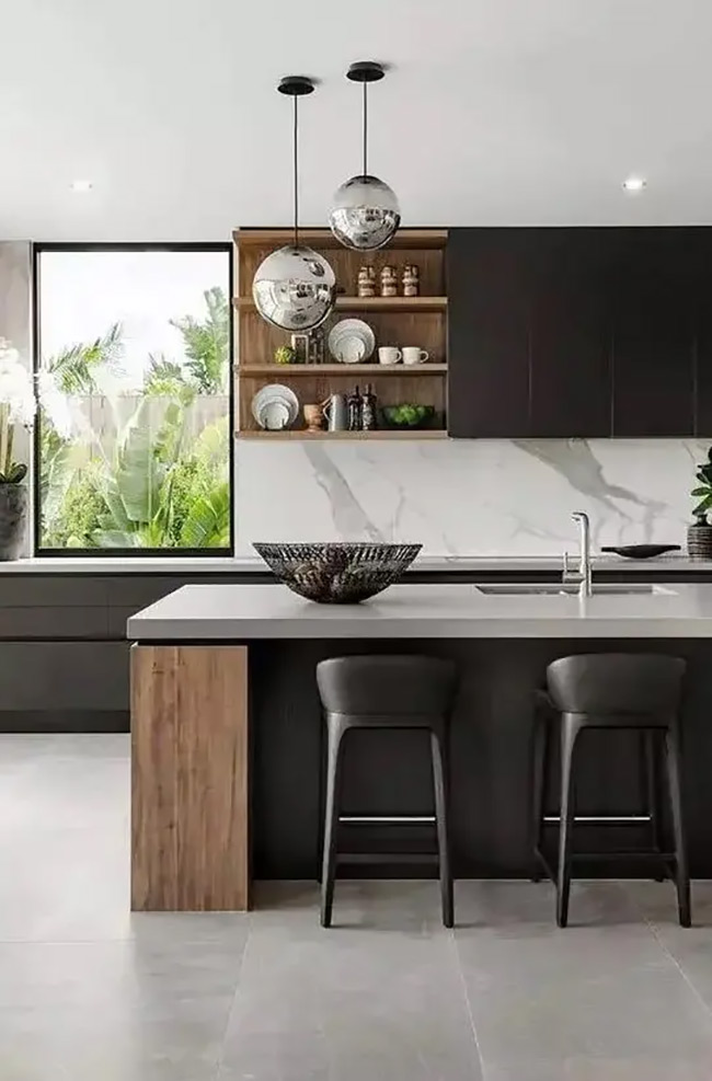 A light wood shelf unit breaks up the solid wall of matte black cabinets. It adds warmth and provides a dedicated space for displaying pretty ceramics. This no door kitchen cabinet design creates a stunning modern contrast.