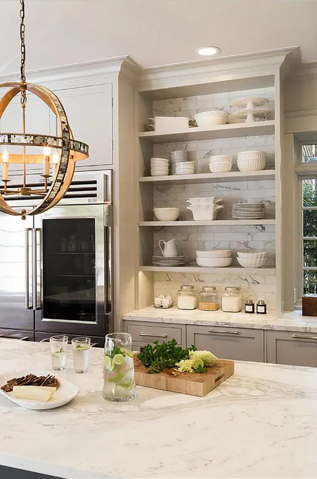 The white marble backsplash continues right up behind the open grey shelves. It creates a seamless and luxurious look for displaying white dishes. This built-in no door kitchen cabinet idea feels very high-end and custom.