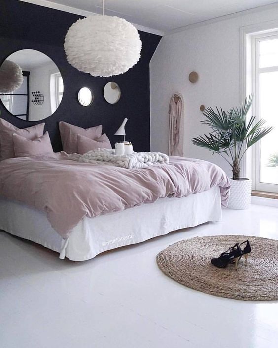 A giant, fluffy white light hangs like a cloud over the bed. It creates a fun focal point in this simple pink and black bedroom.