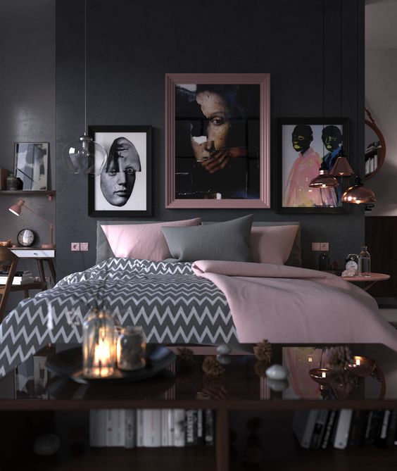 Three portraits hang above the bed to give the room a cool gallery look. The grey chevron duvet cover contrasts nicely with the plain pink blanket. Copper lights add a warm glow to this modern pink and black bedroom.