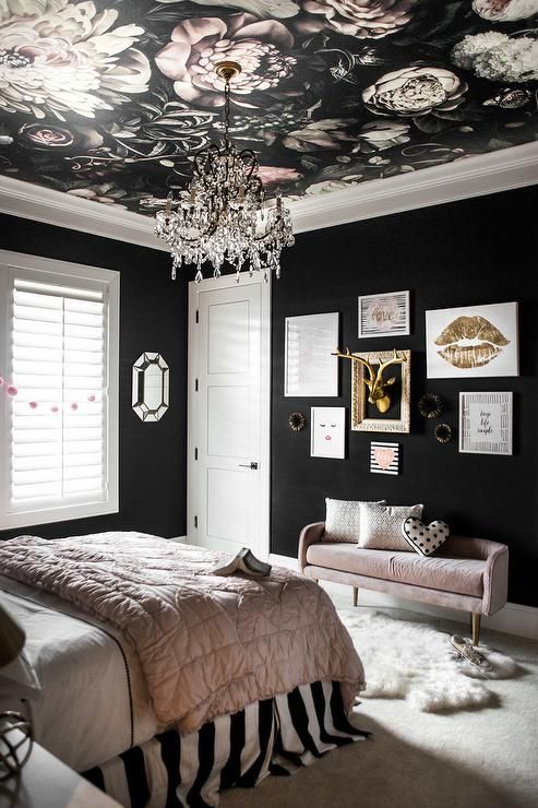 Putting the floral wallpaper on the ceiling is an amazing idea! It looks so fancy with the crystal chandelier hanging right in the middle. The gallery wall with the gold deer head makes the space feel personal and fun. This is definitely a one-of-a-kind pink and black bedroom.