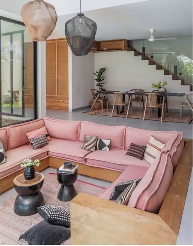A soft pink sofa makes this conversation pit look very calm and inviting. The wood frame and stairs in the back give it a natural, open feel.