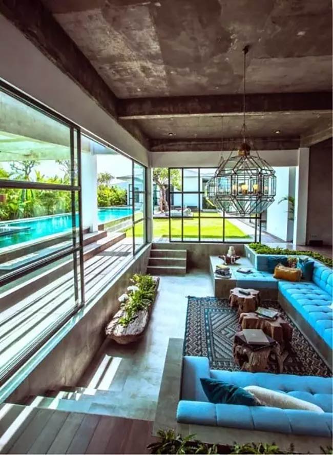 That bright blue sofa really pops in this concrete room. This conversation pit is right next to a pool and has a giant, interesting light.