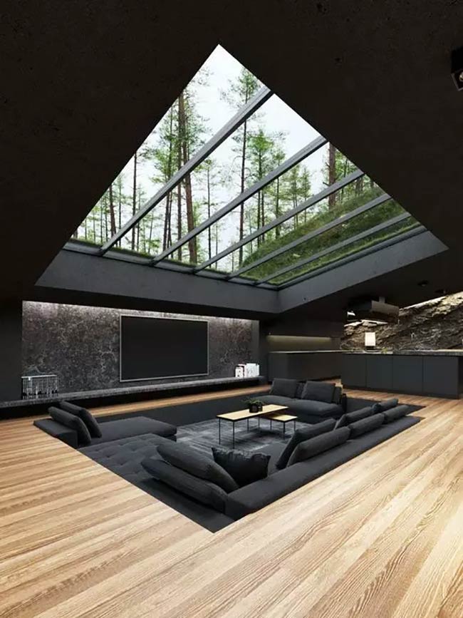 A giant glass ceiling lets you see all the trees. This dark conversation pit is all black, matching the walls and the big TV.