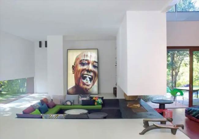 That big, colorful painting of a face really stands out! The green sofa in this sunken area is very bright.