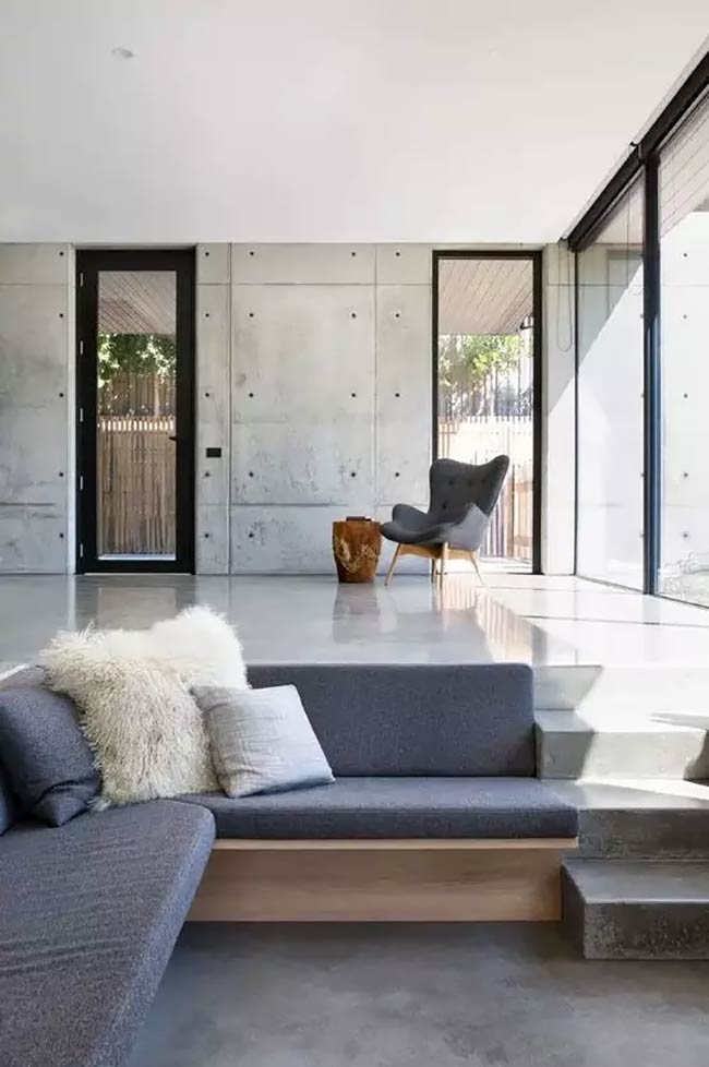 This conversation pit is made of concrete. The simple gray cushions and fluffy pillows look soft on the hard bench.