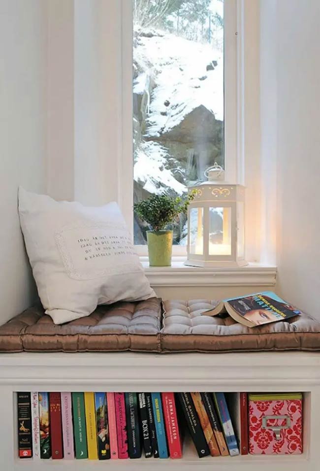 Looking out at the snow from this tiny seat must be magical. The shelf underneath is just big enough for a row of colorful books and a storage box. A white lantern and a soft pillow make this small under window storage corner very inviting.
