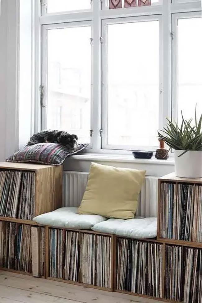 Stacking wooden crates on their sides is a cheap and cool way to store vinyl records. The flat top creates a perfect sunny spot for a dog to nap on a pillow. This rustic under window storage idea adds a lot of character and warmth to the room.
