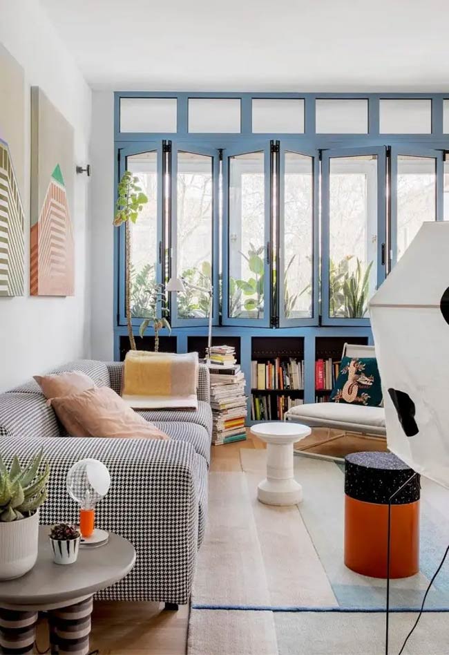 The bright blue paint makes this entire wall look amazing and unique. The folding windows open up completely to let fresh air into the room. It is a very smart under window storage design that keeps books tucked away below the glass.