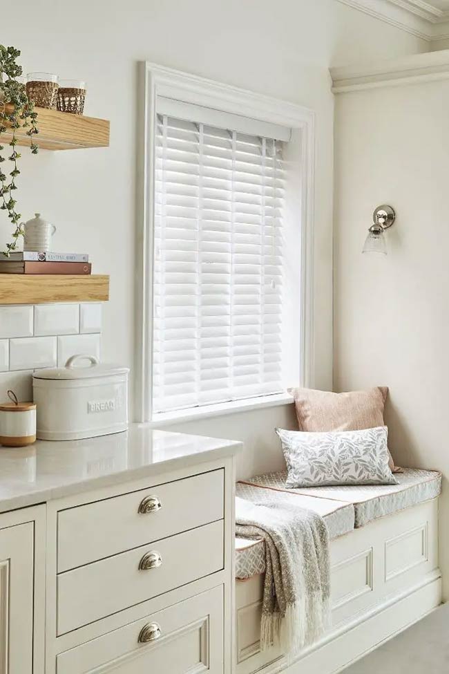 Soft grey cushions make this built-in seat look very comfortable and inviting. The deep drawers underneath offer plenty of under window storage for extra kitchen linens or blankets. It creates a lovely spot to relax next to the white blinds.