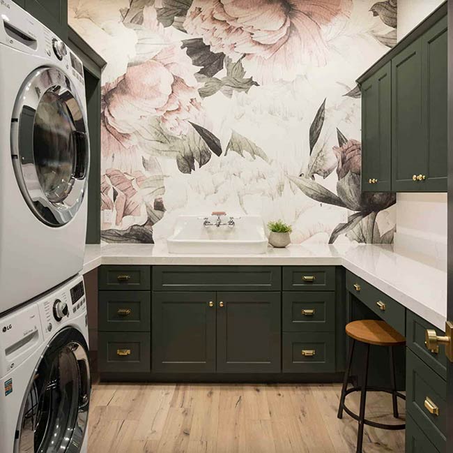 Adding patterned wallpaper transforms a laundry room into a lively, welcoming space. Pink floral designs contrast with crisp white countertops and cabinets. The layout includes a practical sink and durable flooring, keeping the room functional while showing personality. Wallpaper makes even a small laundry area feel like a playful, creative corner of the home.