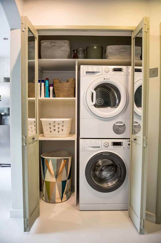 Compact hallway laundry rooms can hide stackable appliances behind bifold doors. Pistachio green cabinets add a gentle pop of color, while the space remains fully functional. Pull-out hampers and shelves ensure that laundry is organized without clutter.