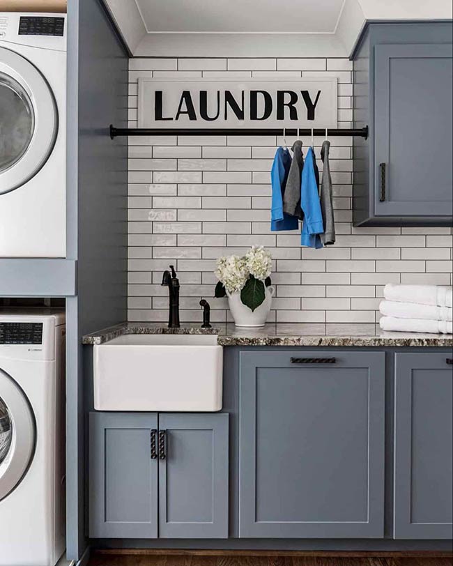 A 10x14 laundry room includes a folding table, hanging rods, pull-out hampers, and a stackable LG washer/dryer. Sliding barn doors keep the space hidden when not in use, while custom cabinets and classic subway tile add style. Every element has a purpose, making chores faster and easier.